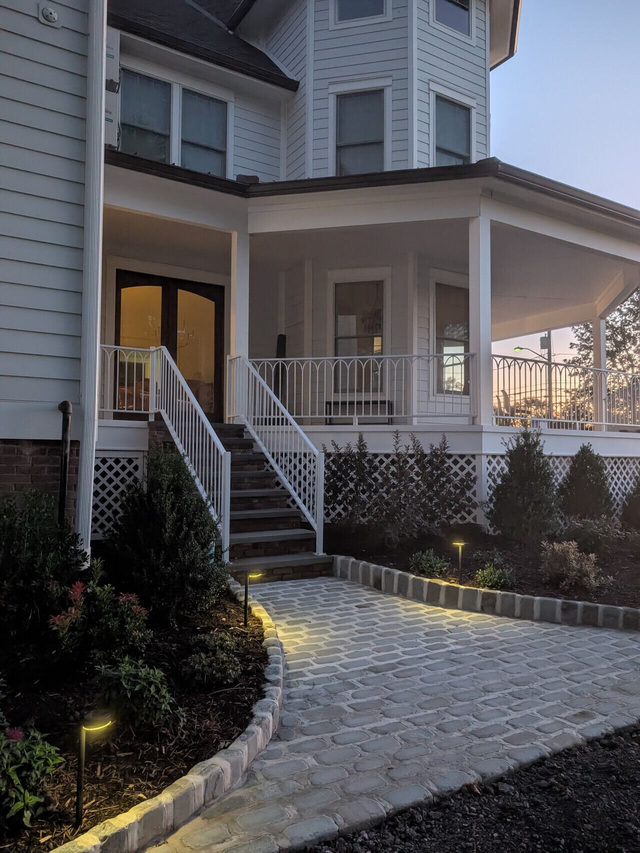 A two-story house with a covered porch and a stone pathway leading to the entrance.