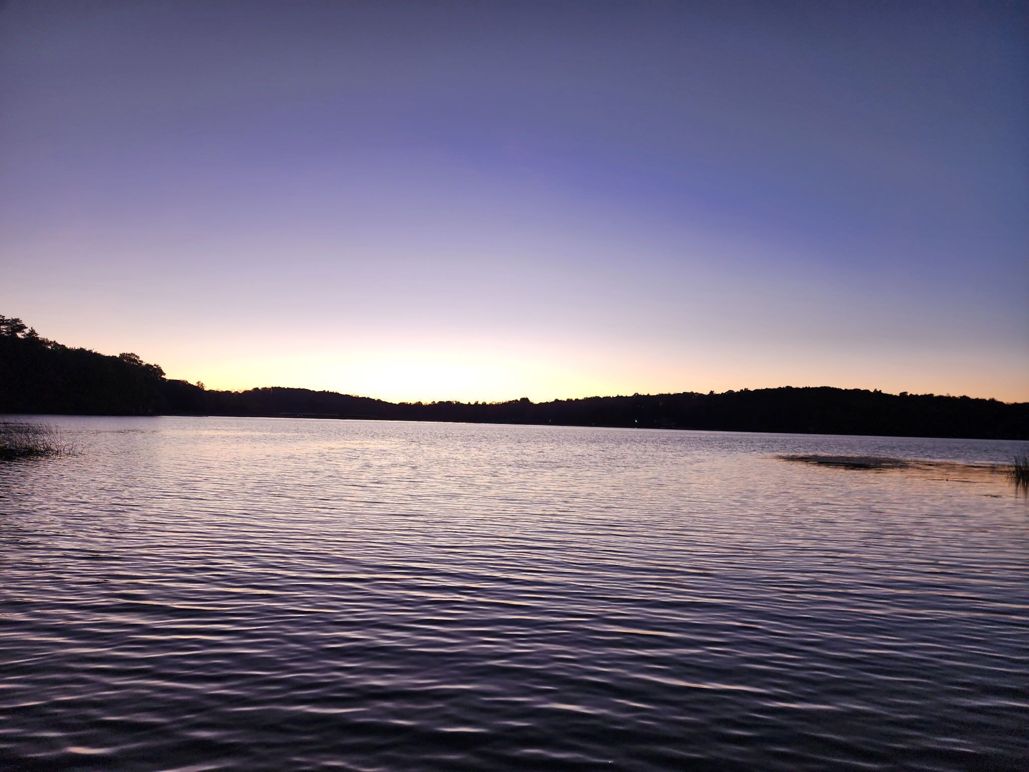 A calm lake at sunset with a clear sky.