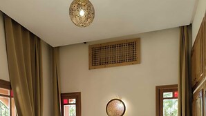 A bedroom with a large bed, two bedside tables with lamps, a decorative wall hanging, and a ceiling light fixture. - Domaine du souffle d'Amaïa  (Sidi Abdallah Ghiat)