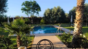 A breakfast setup with a pool view, including a table with plates, cups, and pastries. - Domaine du souffle d'Amaïa  (Sidi Abdallah Ghiat)