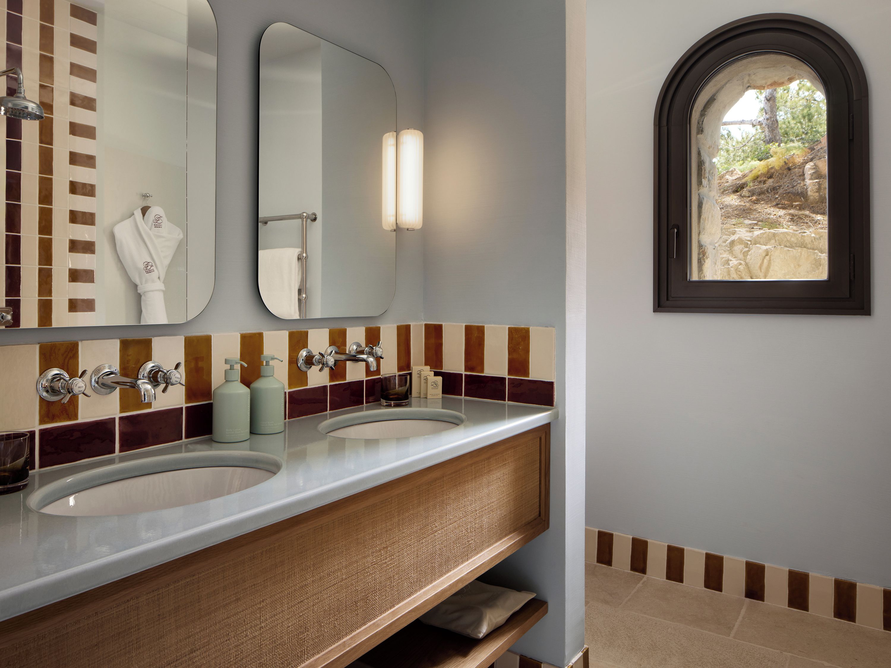 A bathroom with two sinks, a mirror, and a window.