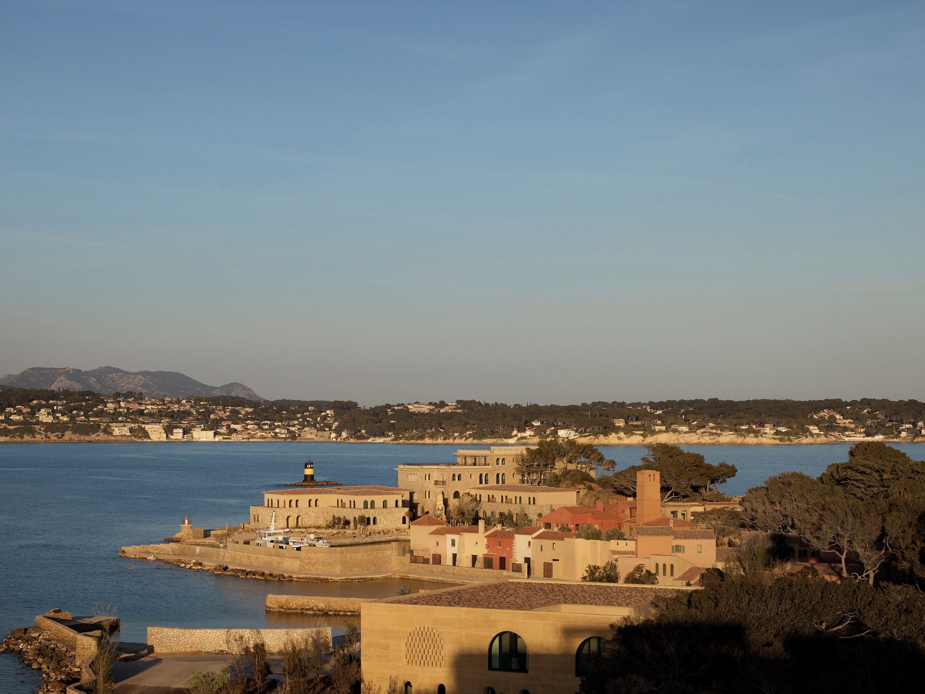 Un pueblo costero con edificios históricos, un faro y una vista despejada del mar.