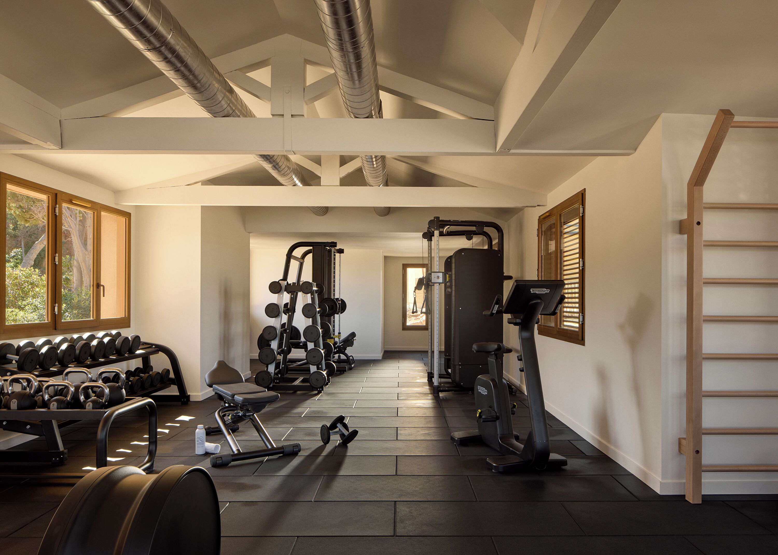 Un gimnasio con equipo de ejercicio, cinta de correr y mancuernas.