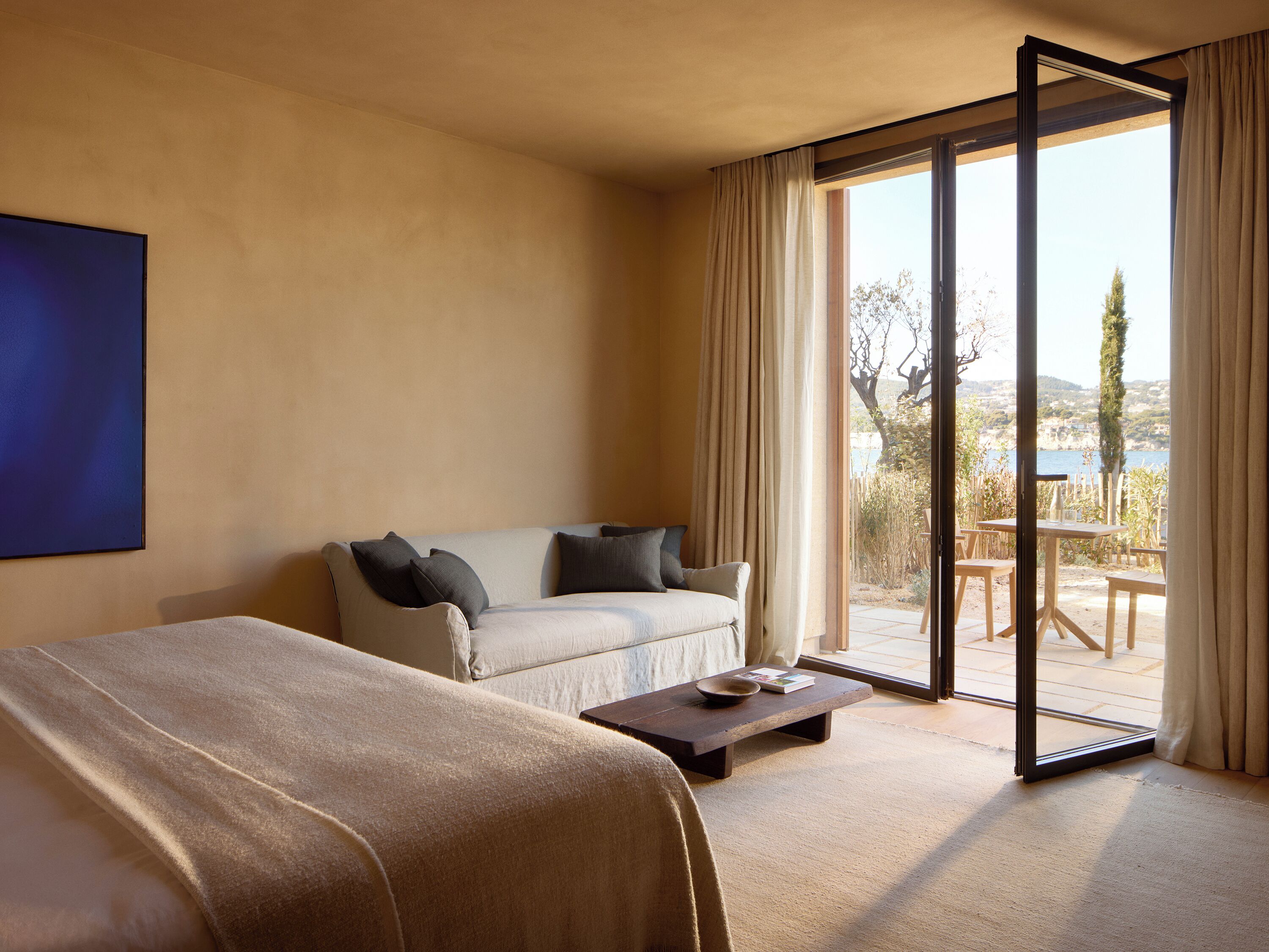 Une chambre d’hôtel avec un lit, un canapé, une table basse et une vue sur l’extérieur.