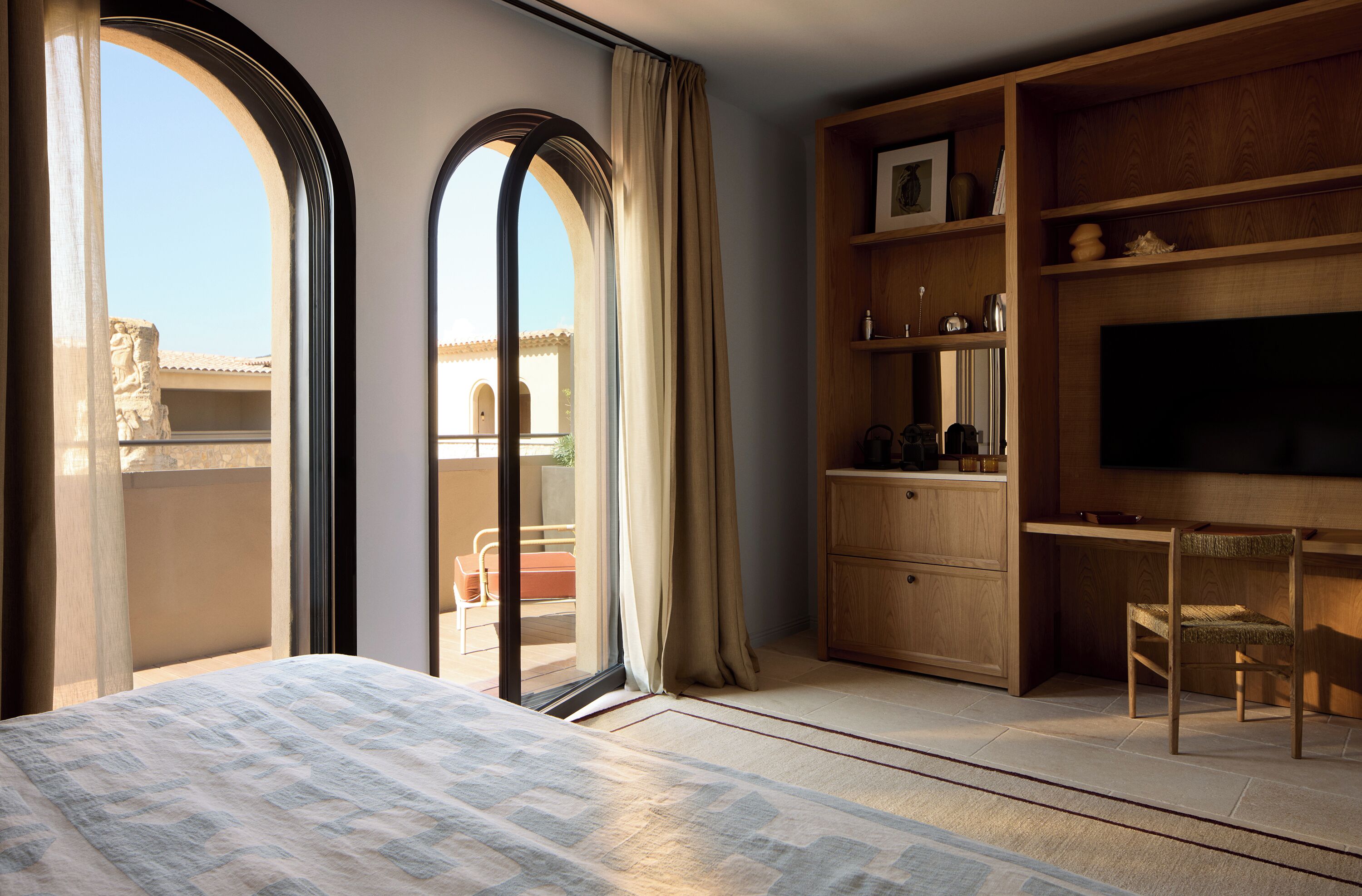 Un dormitorio con una cama grande, un televisor, muebles de madera y vistas a través de una ventana.