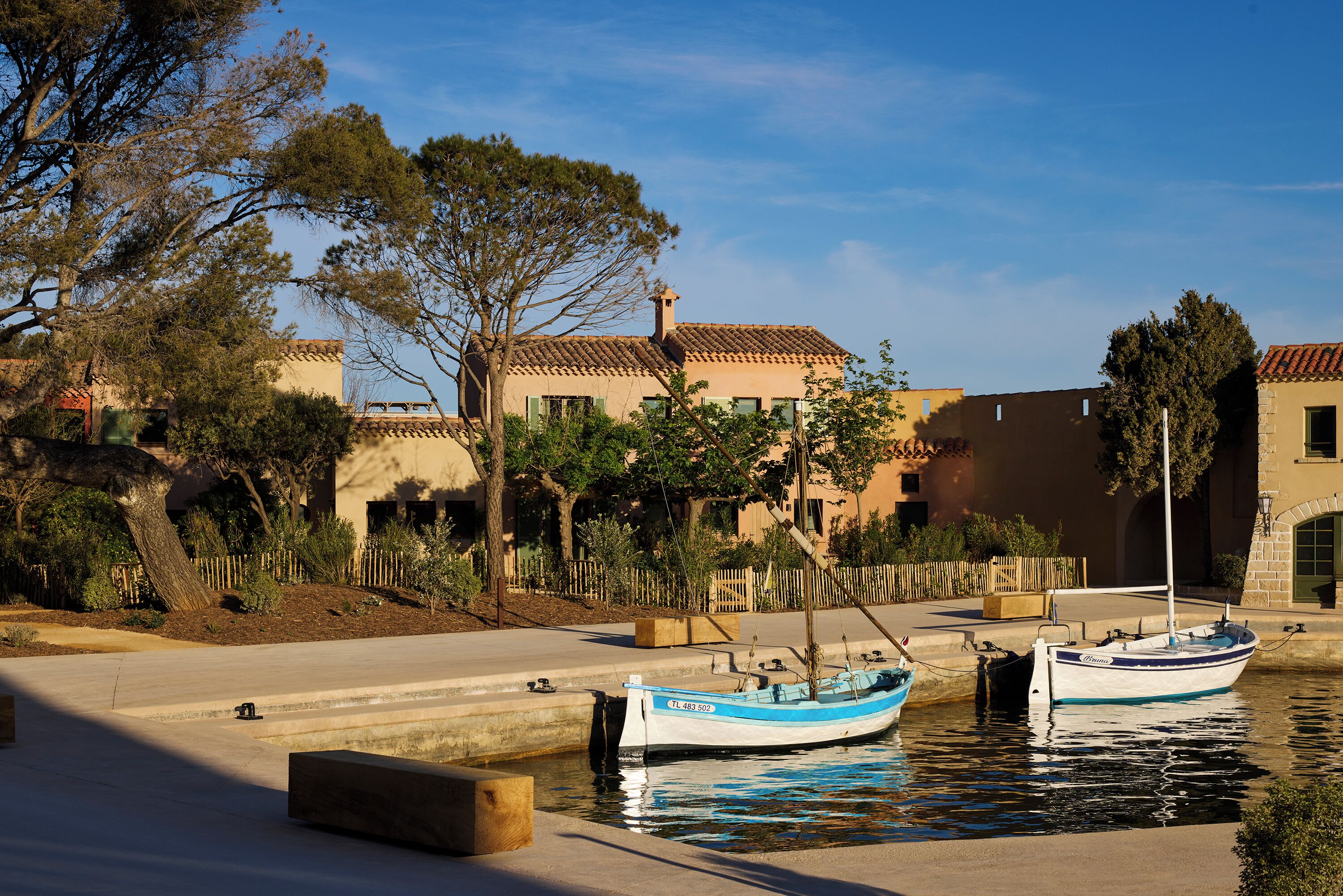 A waterfront property with a dock, boats, and Mediterranean-style buildings.