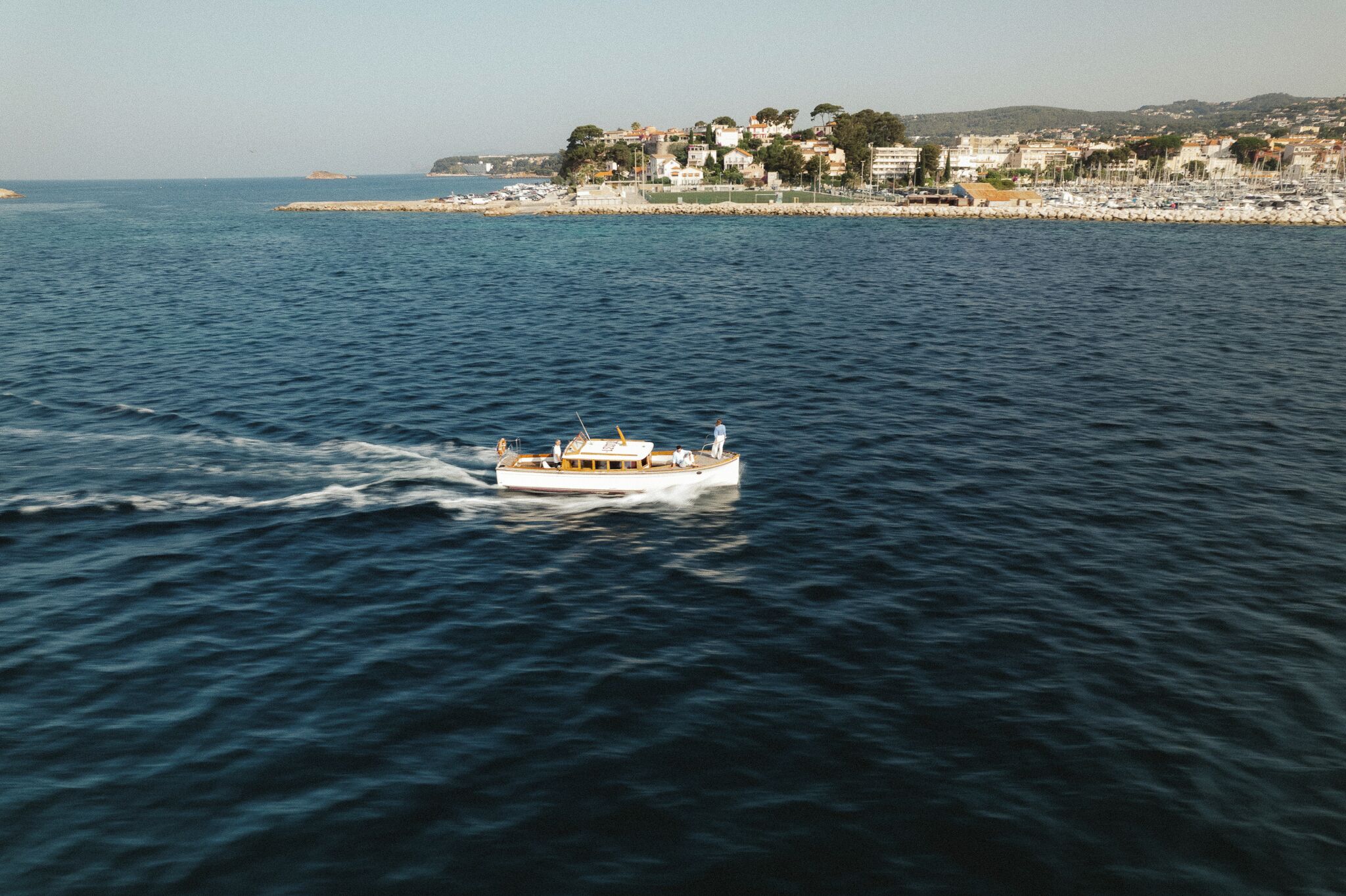 A boat on a body of water with a coastal town in the background.