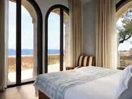 Un dormitorio con cama, cortinas y vistas al mar.