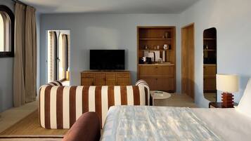 A hotel room with a bed, a sofa, a television, a wooden cabinet, and a small table.
