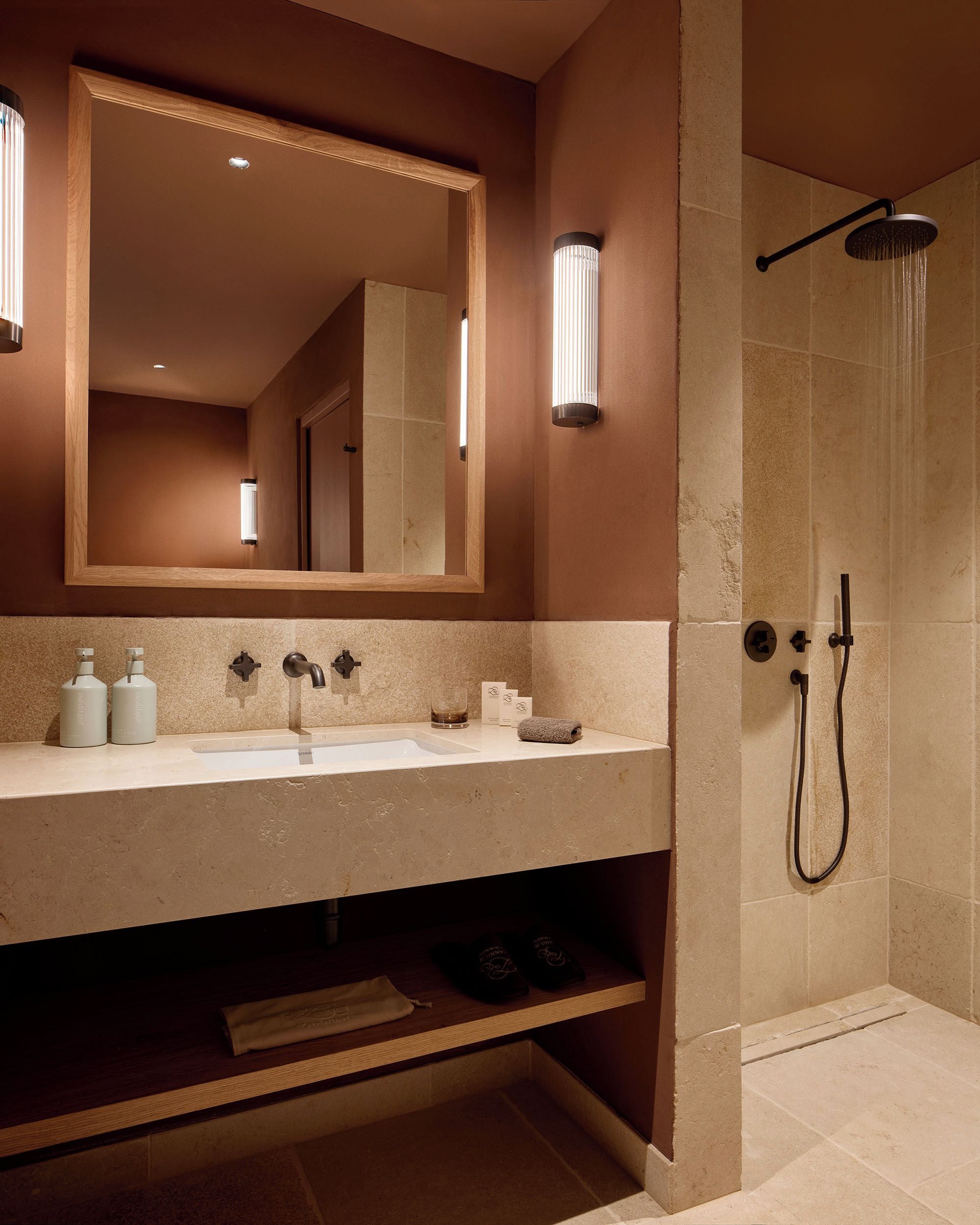 A modern bathroom with a large mirror, a sink with two bottles of soap, and a shower area with a handheld showerhead.