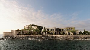 A coastal building with multiple arches and a stone wall. - Zannier Île de Bendor (Bandol)