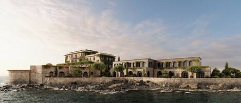 A coastal building with multiple arches and a stone wall.