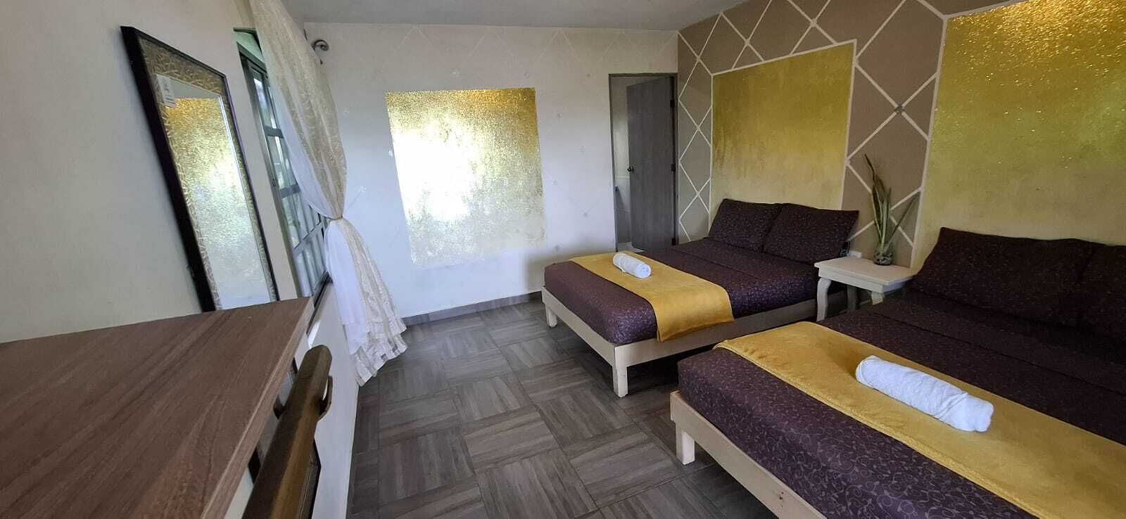 A hotel room with two beds, a wooden desk, and a mirror.