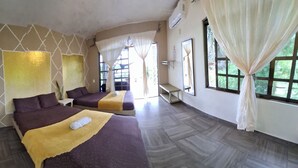 Ein Hotelzimmer mit zwei Betten, einem großen Fenster mit Vorhängen, einer Wand-Klimaanlage und einem kleinen Tisch.
