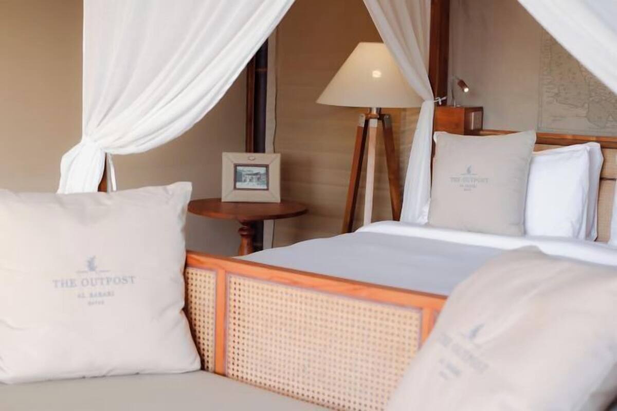 A hotel room with a bed, a nightstand, a lamp, and a picture frame.