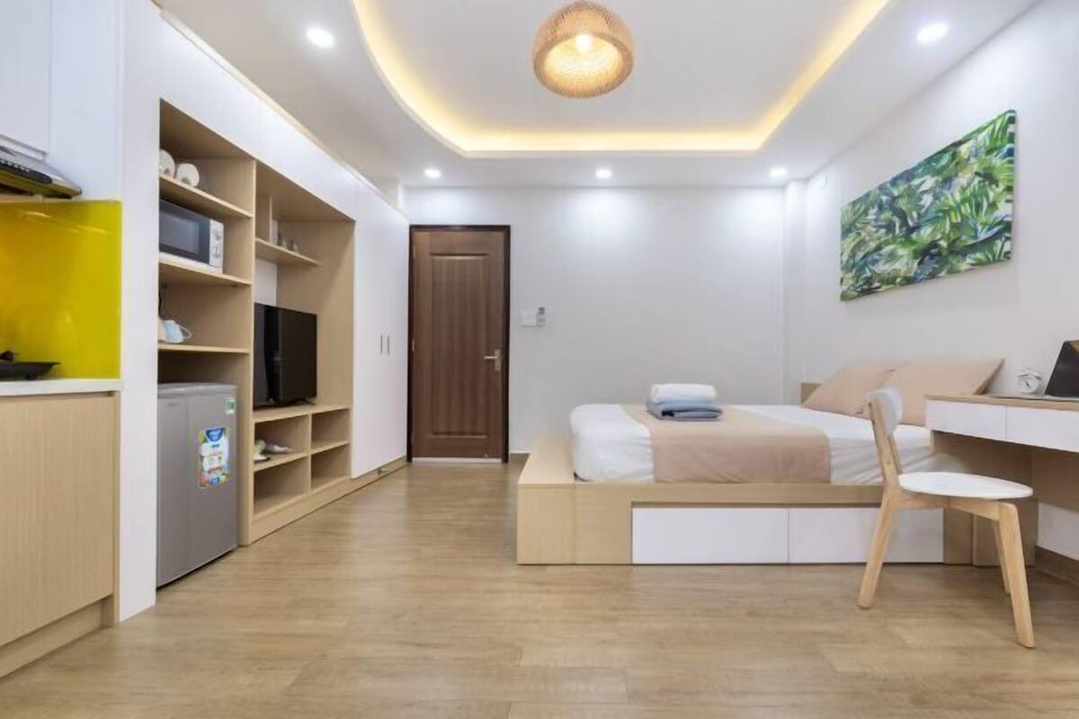 Une chambre compacte comprenant un lit, une table de chevet et une chaise. Il y a également un coin cuisine avec un réfrigérateur et un four à micro-ondes.