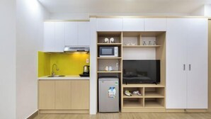 A compact kitchen with a microwave, refrigerator, and a flat-screen TV. - Cozrum Homes - Yoga Corner (Ho Chi Minh City)