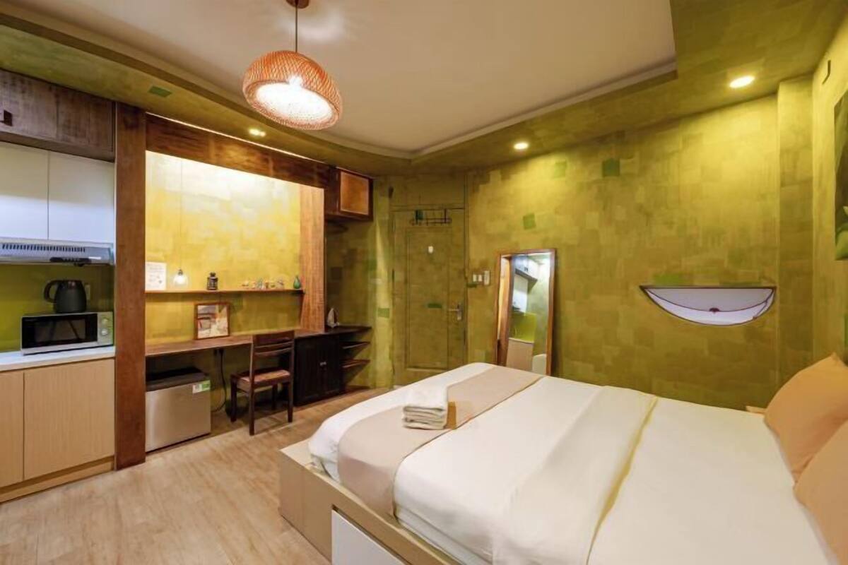 Une chambre d’hôtel équipée d’un lit, d’un bureau, d’une chaise, d’un four à micro-ondes et d’un petit réfrigérateur.