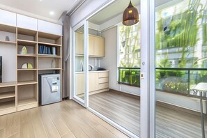 A modern kitchen with built-in appliances, a dining area with a table and chairs, and a large sliding glass door leading to a balcony. - Cozrum Homes - Yoga Corner (Ho Chi Minh City)