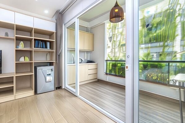 A modern kitchen with built-in appliances, a dining area with a table and chairs, and a large sliding glass door leading to a balcony. - Cozrum Homes - Yoga Corner (Ho Chi Minh City)