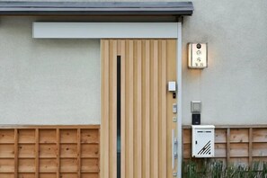 Une porte en bois dotée d’une poignée verticale, un interphone fixé au mur et un coffre-fort avec un clavier numérique.