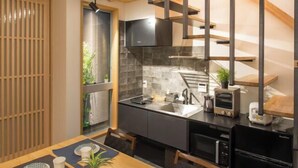 Een moderne keuken met een ingebouwde kookplaat, een spoelbak en een houten eettafel met stoelen.