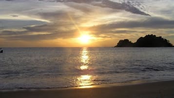 Un atardecer sobre un mar tranquilo con una isla distante.