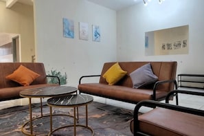 A room with two leather sofas, a round table, and wall art. - Forget-Me-Not Pangkor Homestay 70 (Pangkor)
