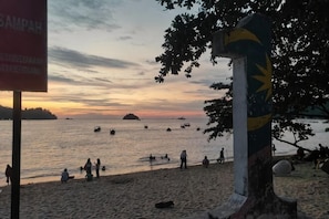 A beach with people, a sign, and a large pillar. - Forget-Me-Not Pangkor Homestay 70 (Pangkor)
