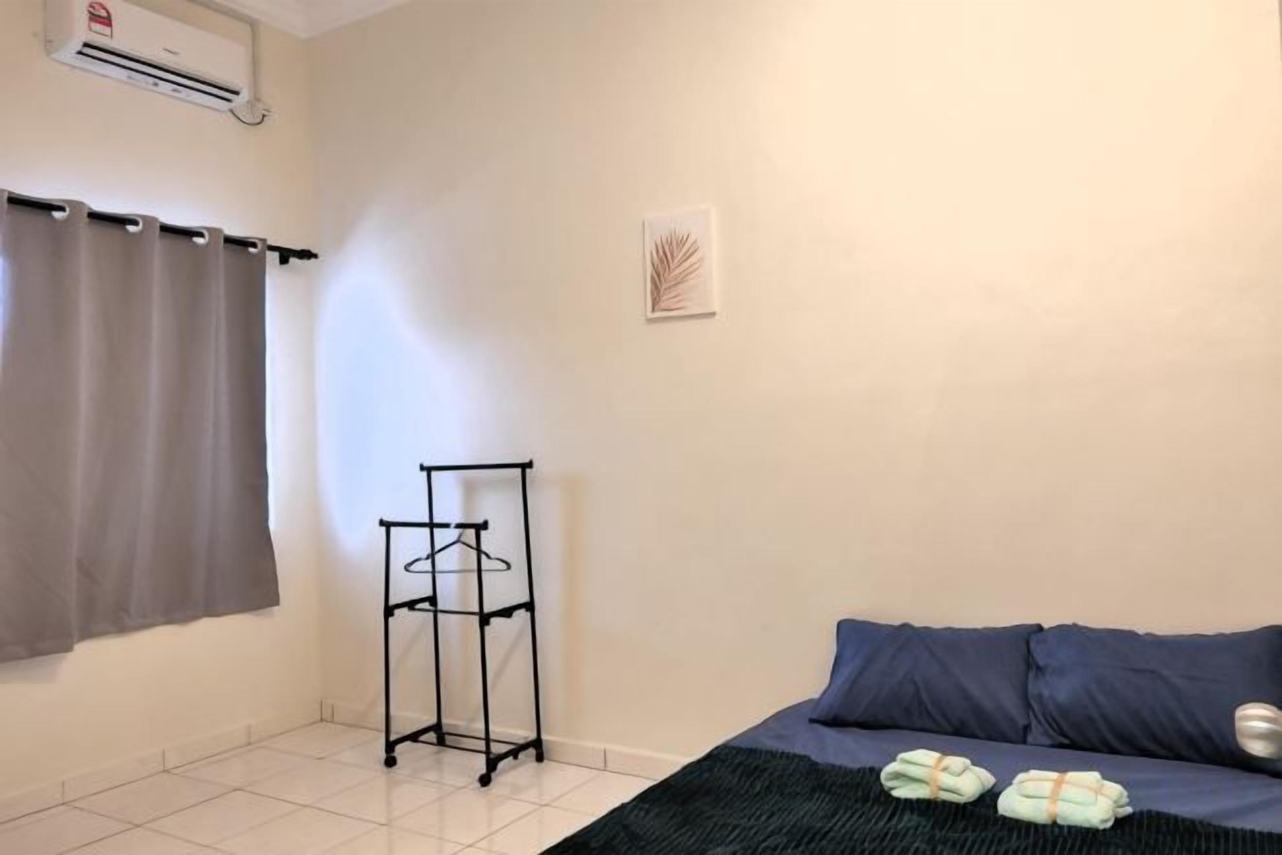 Quarto com cama, porta-toalhas e ar-condicionado na parede.