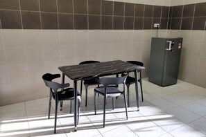 Ein kleiner Essbereich mit Tisch und Stühlen, einem Kühlschrank und gefliesten Wänden.