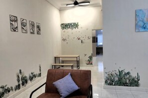 A hallway with a brown chair, a table, and a ceiling fan. - Forget-Me-Not Pangkor Homestay 70 (Pangkor)