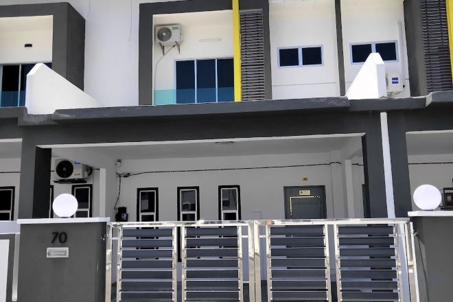 Un edificio de varios pisos con entrada protegida por una reja, unidades de aire acondicionado y una serie de puertas.