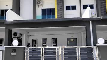 Un edificio de varios pisos con entrada protegida por una reja, unidades de aire acondicionado y una serie de puertas.