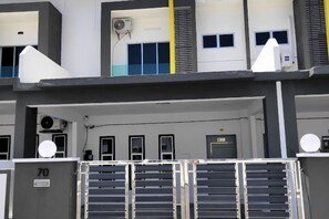 A multi-story building with a gated entrance, air conditioning units, and a series of doors. - Forget-Me-Not Pangkor Homestay 70 (Pangkor)