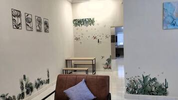 A hallway with a brown chair, a table, and wall art.