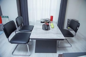 A conference room with a marble table, black chairs, and a small table with a fruit bowl and red cups. - Minguzar Hotel (Tashkent)