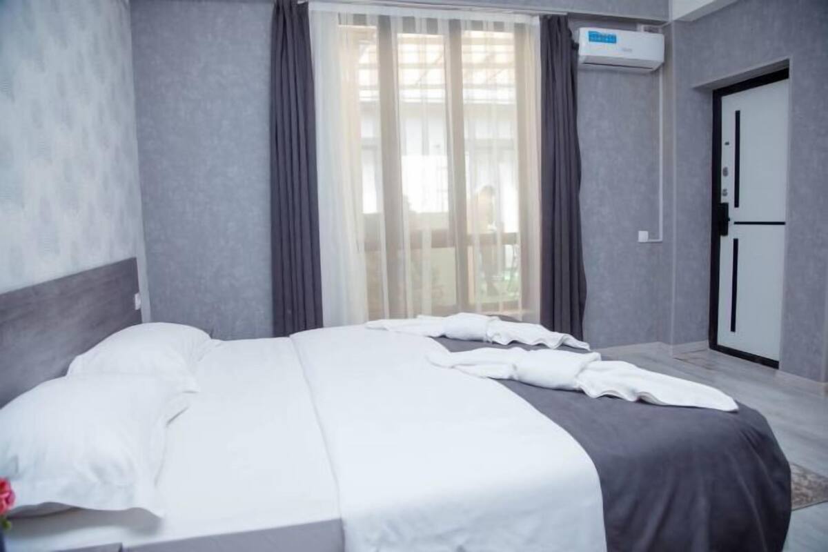 A hotel room with a bed, a sliding glass door, and an air conditioning unit.