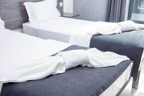 A hotel room with two beds, each with a white bedspread and a grey headboard. - Minguzar Hotel (Tashkent)