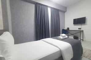 A hotel room with a bed, a desk, a chair, a TV, and a window with curtains. - Minguzar Hotel (Tashkent)