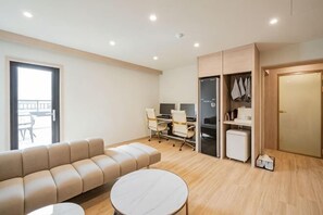 Una sala de estar moderna con un sofá, una mesa redonda, un escritorio con una computadora y un armario.