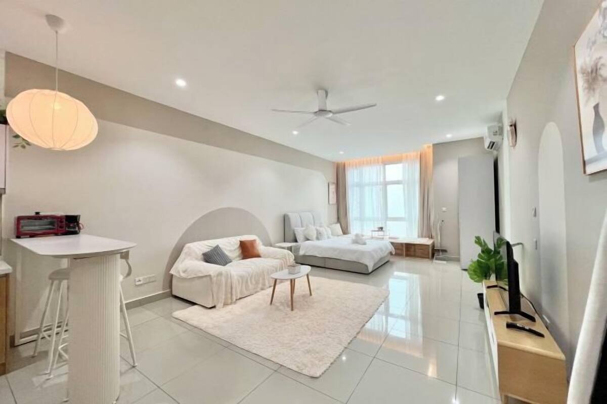 A modern bedroom with a bed, bedside tables, a desk, and a hanging light fixture.