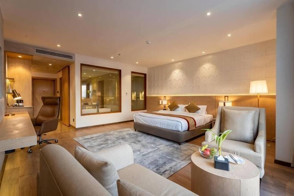 A modern hotel room with a bed, a desk, a sofa, and a coffee table.