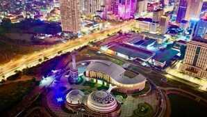 A cityscape with a prominent circular building complex, surrounded by roads and other buildings.
