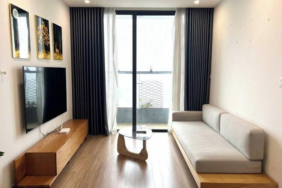 Una sala de estar moderna con una televisión de pantalla plana, un sofá, una mesa de centro y vistas al balcón.