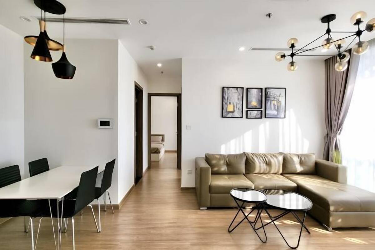 Una sala de estar moderna con un sofá, una mesa de centro, una mesa de comedor y sillas. Hay dos obras de arte enmarcadas en la pared.