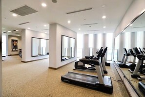 A gym with treadmills, exercise bikes, and a mirrored wall.