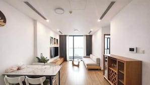 A modern living room with a dining area, a sofa, a TV, and a wooden cabinet.