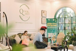 A reception area with a logo on the wall, a reception desk, and a seating area with a couch and chairs. - Vinhomes Skylake My dinh Hanoi-Nanahousing (Hanoi)