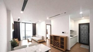 A modern living room with a sofa, dining table, and kitchen area.